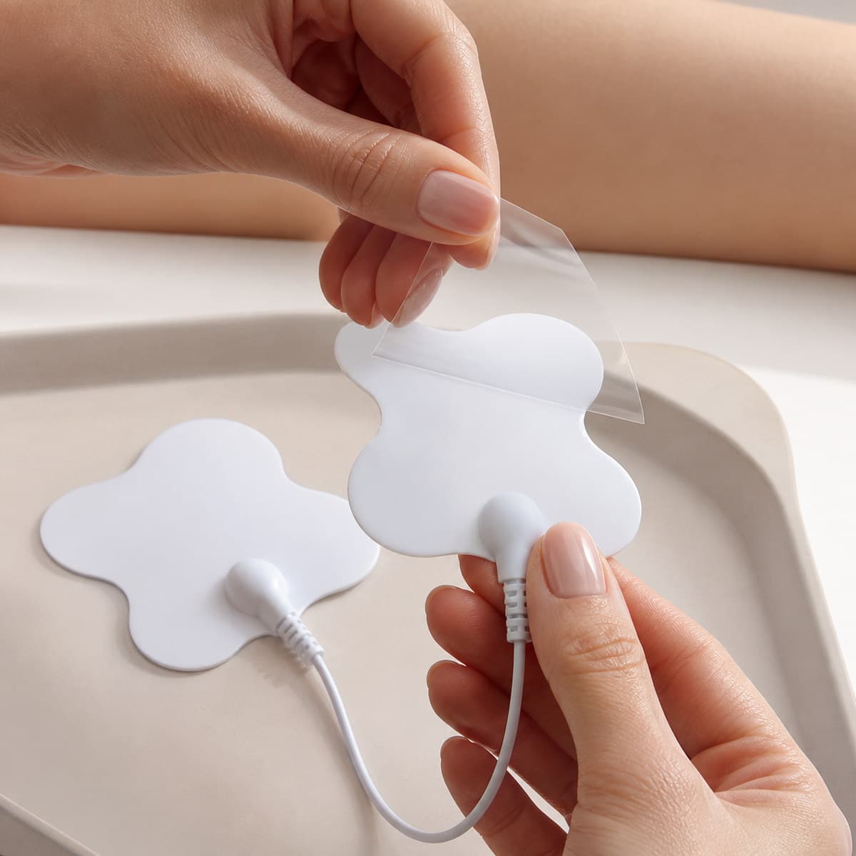 Manos retirando una película transparente de un electrodo blanco reutilizable